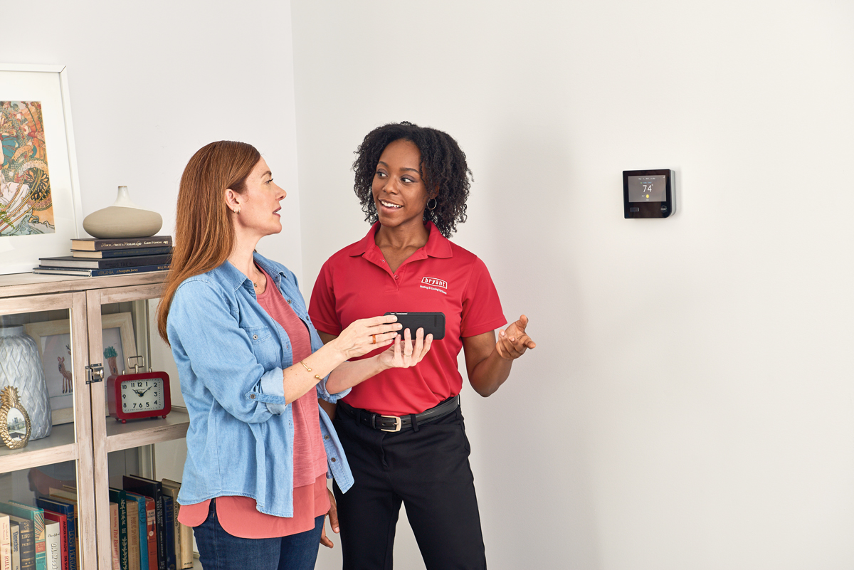 technician with thermostat and homeowner, Bob's Heating & AC