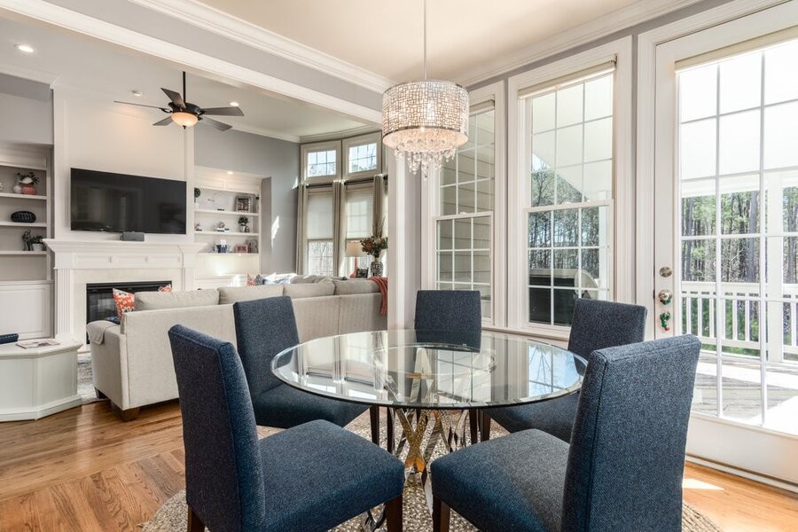 An open-concept living space with table and chairs in the foreground and a couch TV in the background.