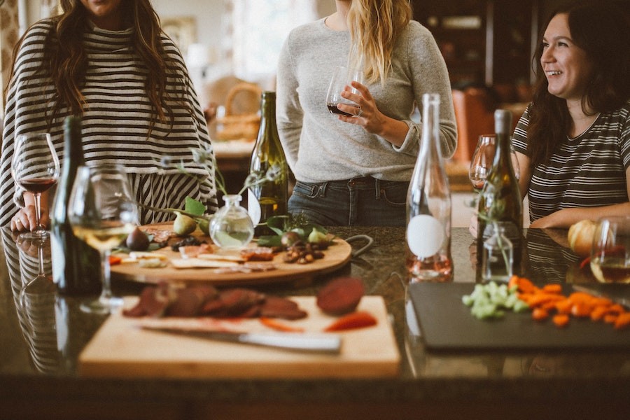 a group of women gathered around a holiday table display featuring food and beverages