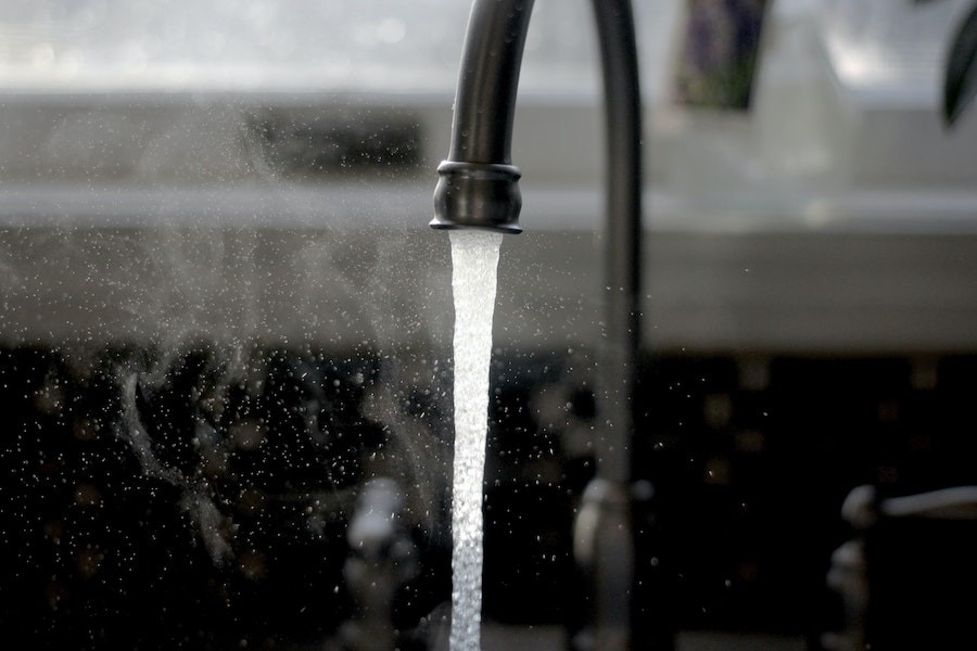 Closeup detail of a kitchen sink faucet running water