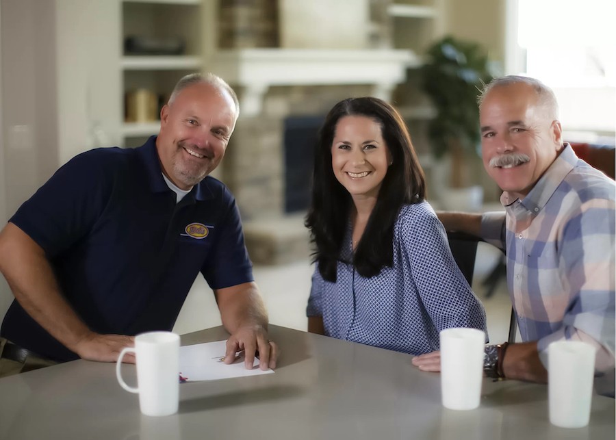 two men and one woman sitting at a table discussing business