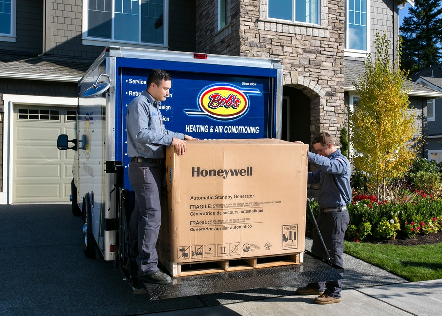 The Bob’s Heating team unloading a generator from a truck in a house’s driveway. 