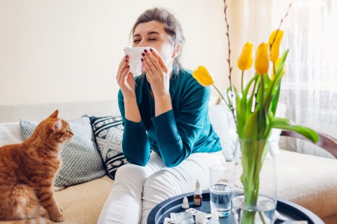 A woman blowing her nose into a tissue.