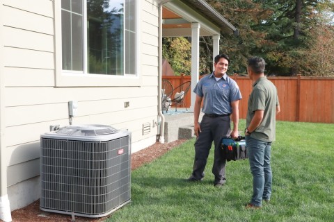 Bob’s Heating technicians installing an AC unit outdoors. 