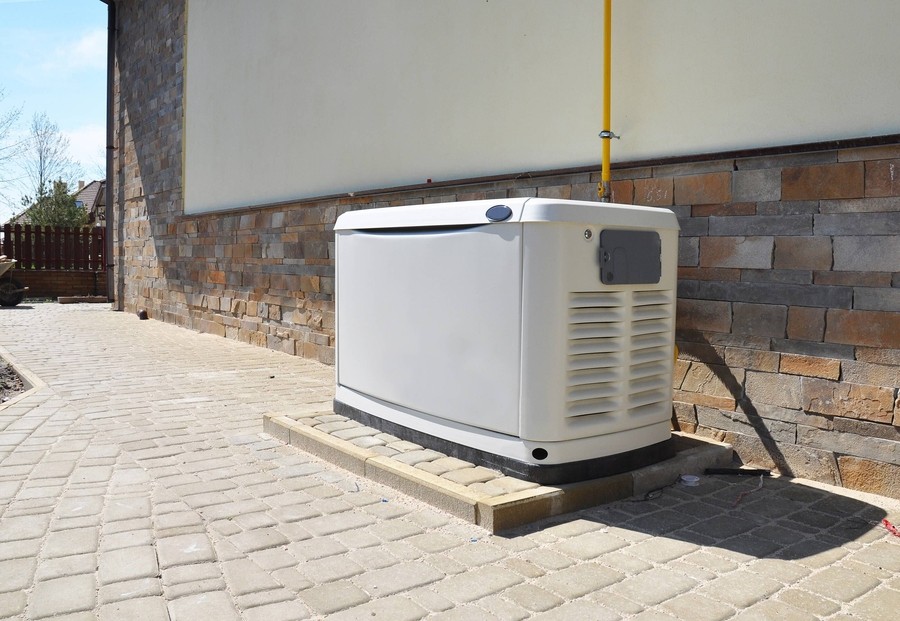  a whole-home generator installed next to a brick building.