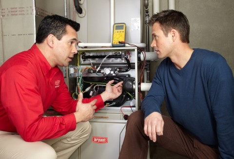 A Bryant service technician shows a customer troubleshooting tips for his furnace.