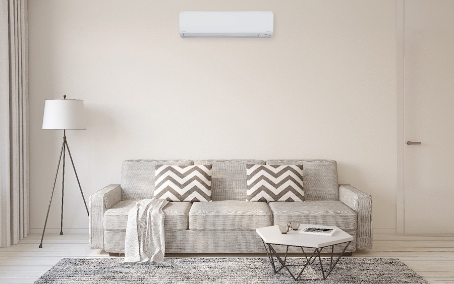 A bright living room with an air quality system mounted high on the wall. 