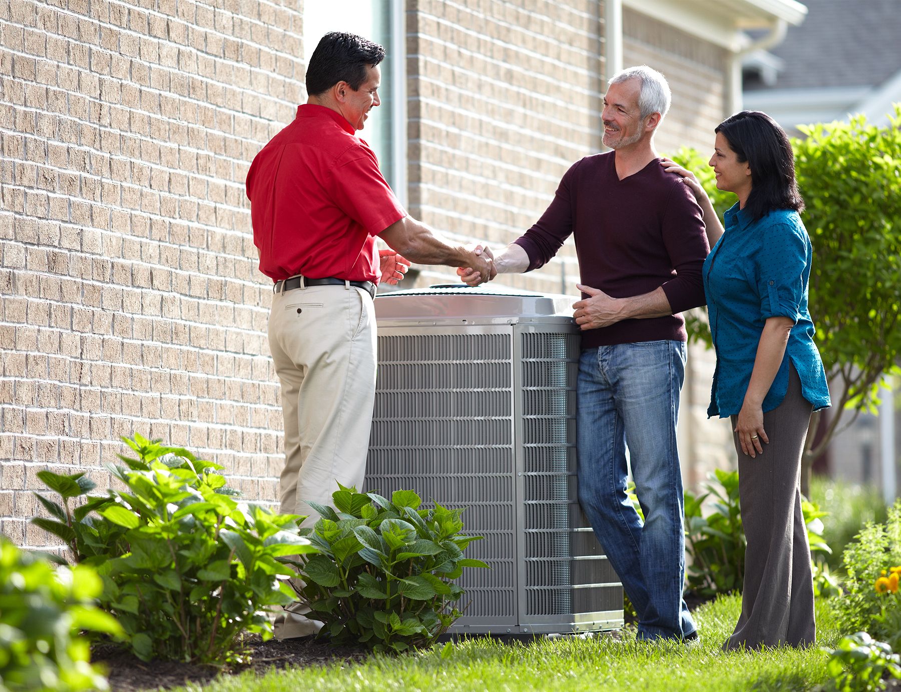 individuals shaking hands next to an HVAC unit outdoors | Bob's Heating & Air Conditioning