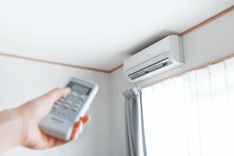 A hand pointing a remote at a ductless mini-split unit