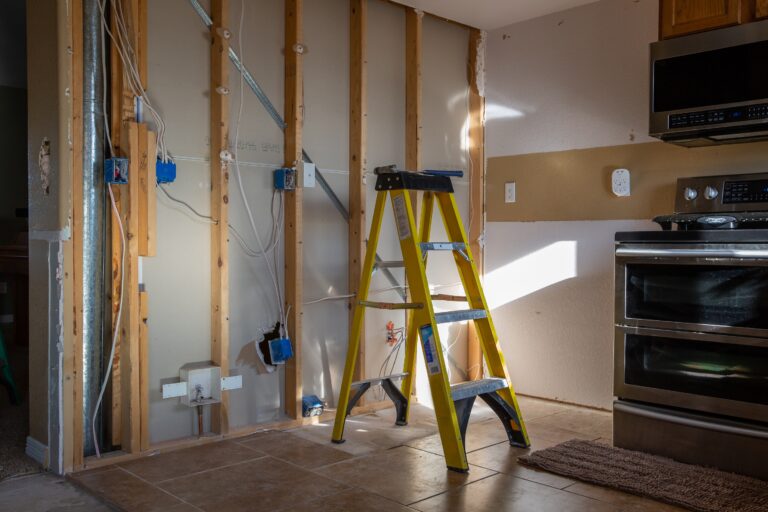 A kitchen mid-build with open wall framing, new wiring and a ladder