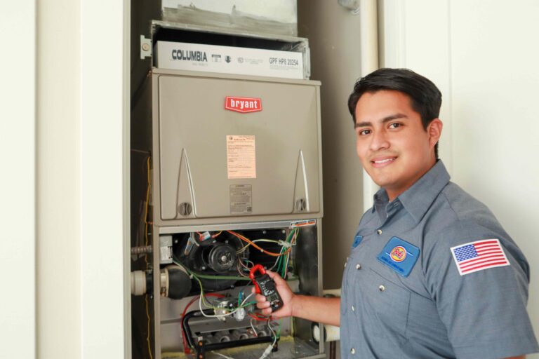 A smiling Bob’s technician beside the furnace he’s servicing