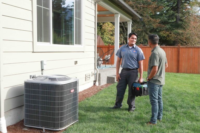A Bob’s technician talking with homeowners beside a new outdoor heat pump