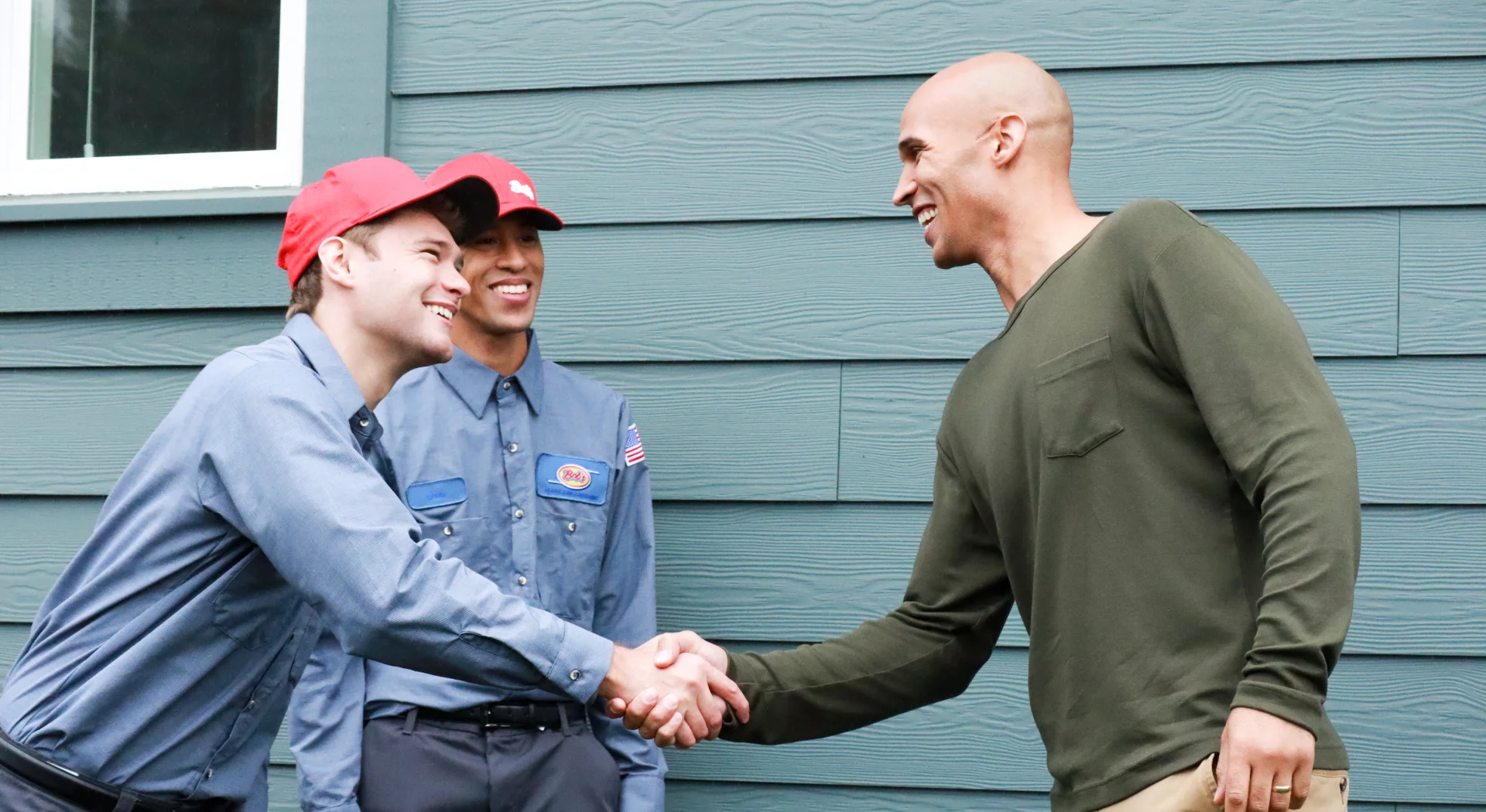 Two Bob’s technicians shaking hands with a homeowner outside his house